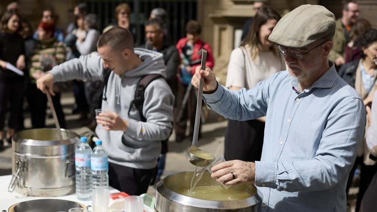 Dos voluntarios ofrecen caldo a personas sin techo.