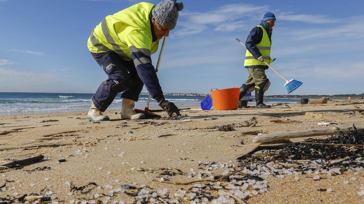 Operarios retiran pellets en una playa de A Coruña.