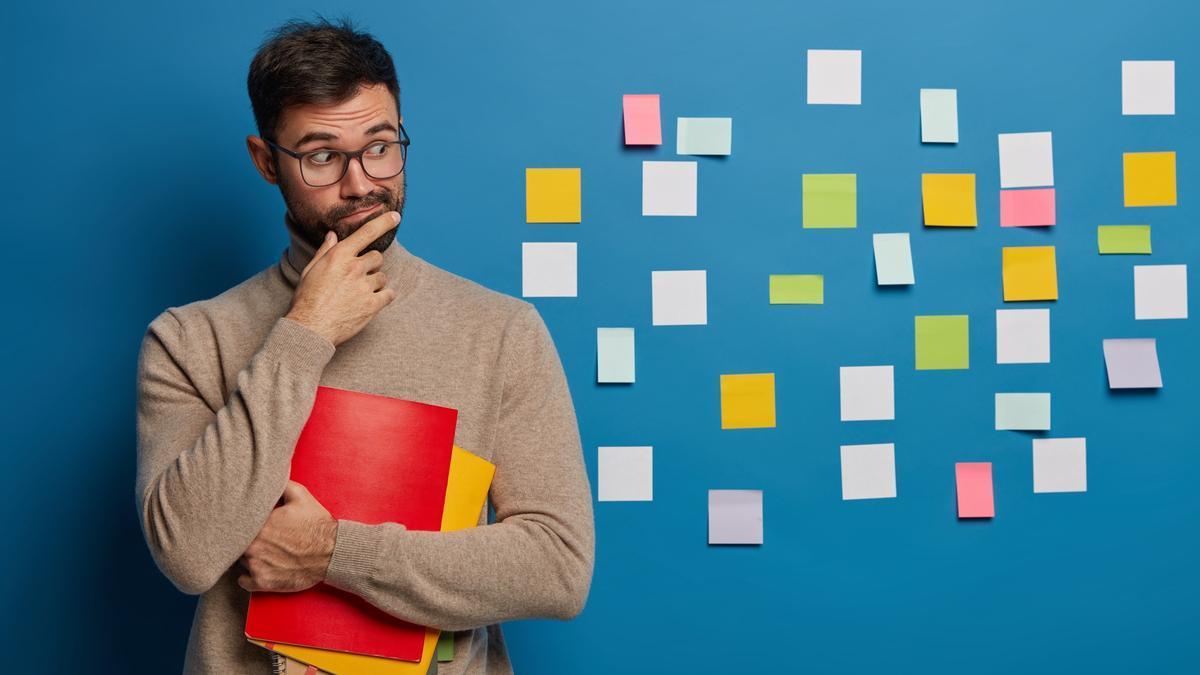 Un hombre posa delante de decenas de post-it.