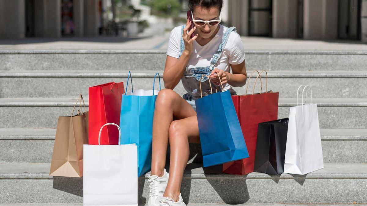 Una mujer rodeada de bolsas en las rebajas de verano.