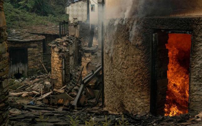 Vista de viviendas ardiendo en la aldea de San Vicente, este lunes en Vilamartín de Valdeorras (Ourense).