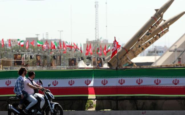 Iraníes pasan junto a los misiles expuestos sobre una pancarta en la que aparece el presidente de EE.UU, Donald Trump, en Teherán.