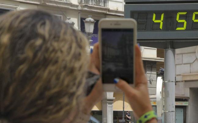 Una mujer fotografía la temperatura de un termómetro que marca 45 grados.