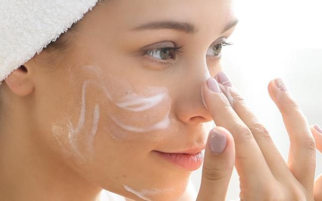 Una mujer se aplica crema en el rostro.