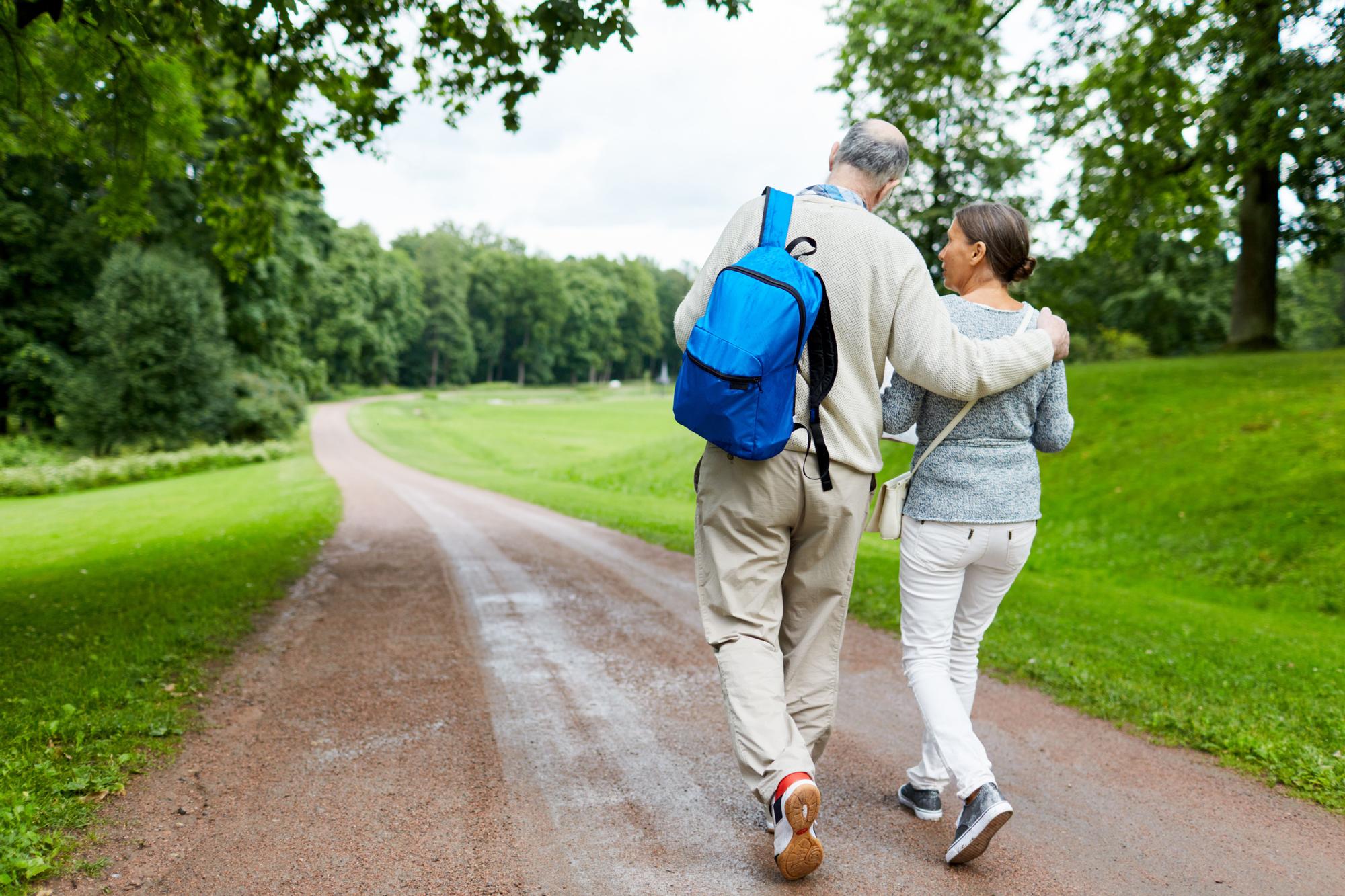 Pareja da un paseo por una zona verde.