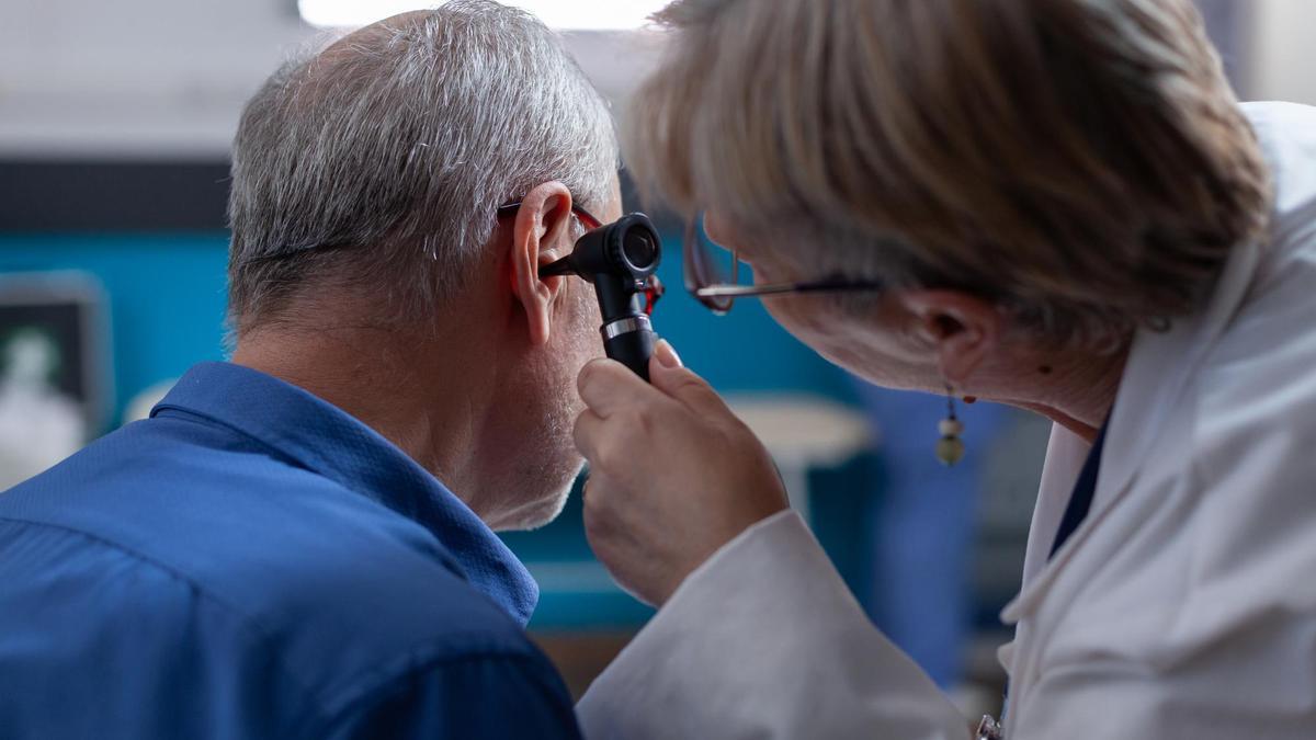 Una otorrino mira con un otoscopio el oído de un paciente.