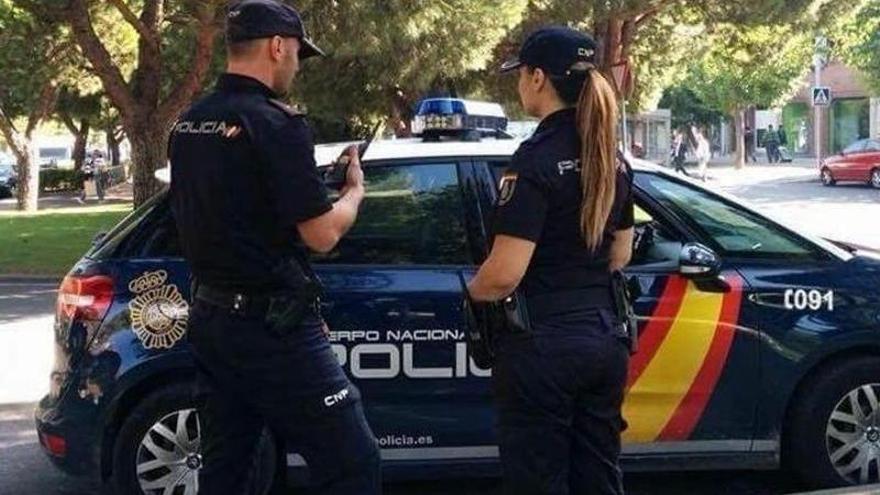 Dos agentes de la Policía Nacional frente a su vehículo.