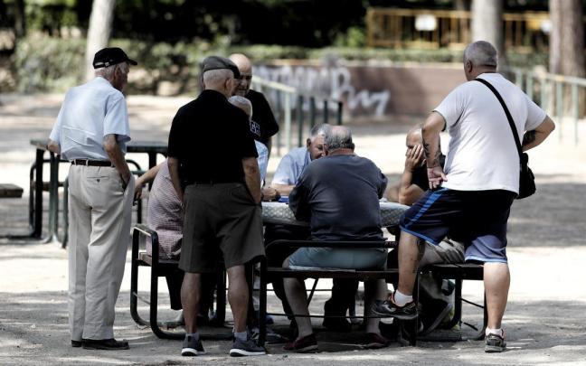 Varios pensionistas juegan al dominó en un parque de Madrid.