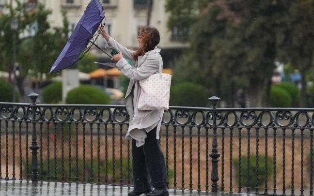 Una mujer trata de refugiarse de la lluvia.