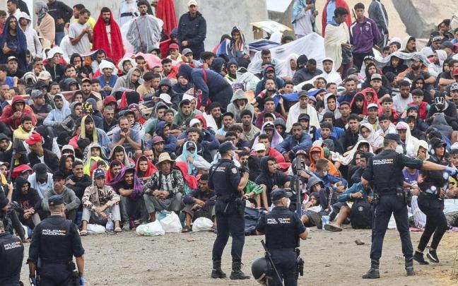 Agentes de Policía vigilan a migrantes que permanecen en la playa del Trampolín, en Ceuta.