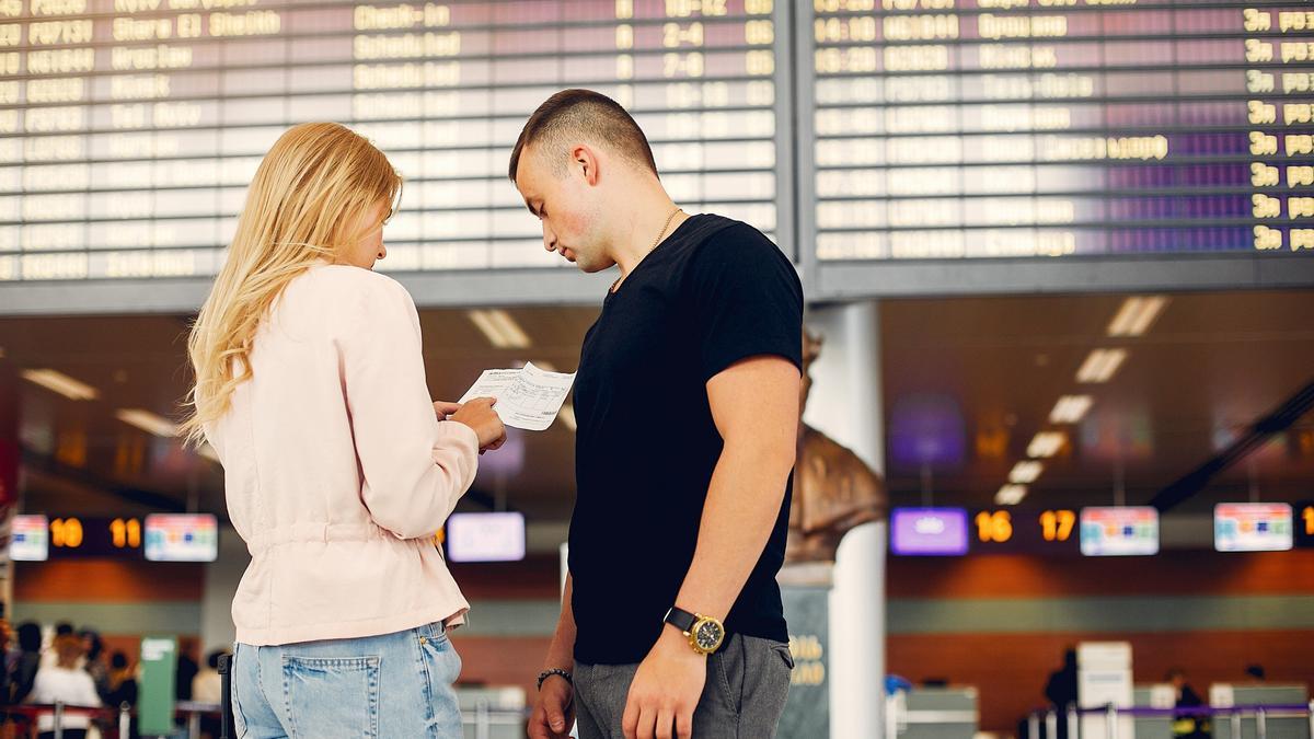 Una pareja comprueba la hora de salida de su vuelo en el panel del aeropuerto.