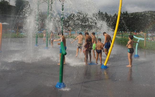 Un grupo de niños se divierte en el parque de chorros de agua de las piscinas de MIntxeta en Elgoibar.