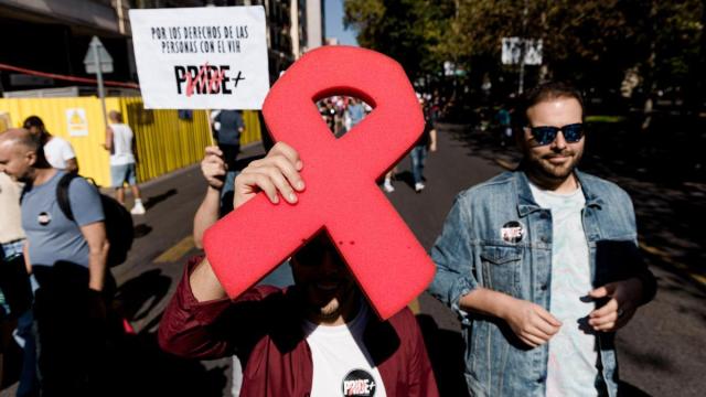 Manifestantes portan un lazo rojo y pancarta con lema 'Por los derechos de las personas con VIH'