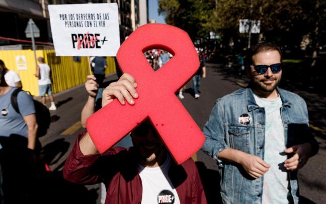 Manifestantes portan un lazo rojo y pancarta con lema 'Por los derechos de las personas con VIH'