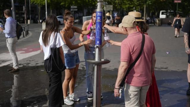 Varias personas se refrescan en una fuente de París.