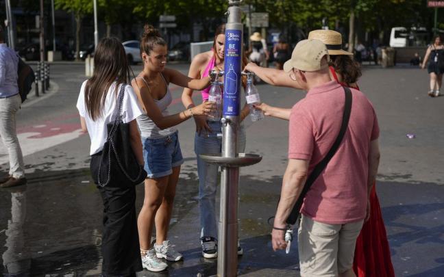 Varias personas se refrescan en una fuente de París.