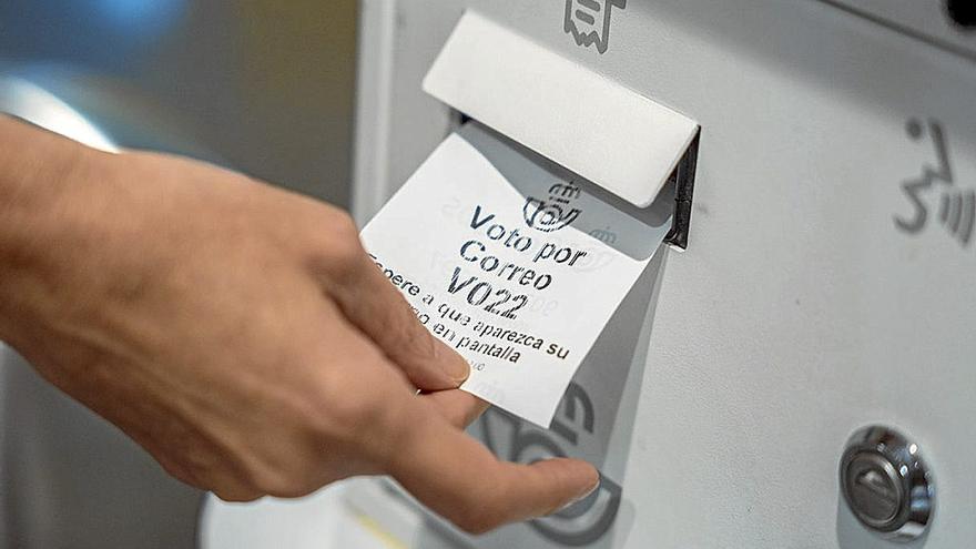 Una persona recoge el tique para solicitar el voto por correo. | FOTO: E. P.