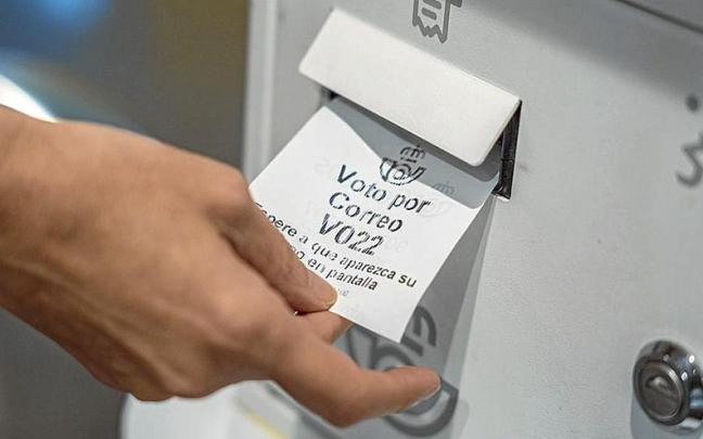 Una persona recoge el tique para solicitar el voto por correo. | FOTO: E. P.