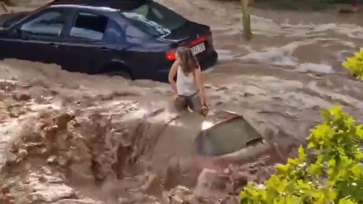 Una joven encima de su coche durante la tromba de agua.