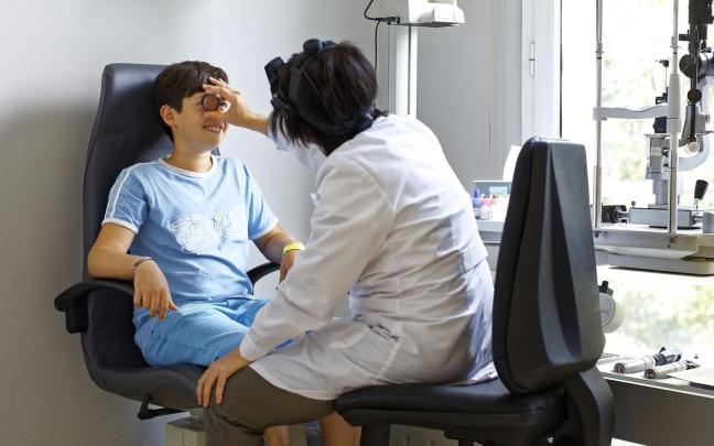 Una oftalmóloga realiza una revisión ocular a un niño en una clínica vizcaina.