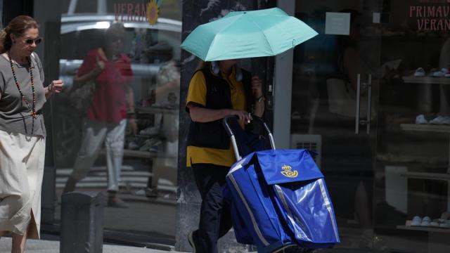 Una cartera se protege del sol con un paraguas.