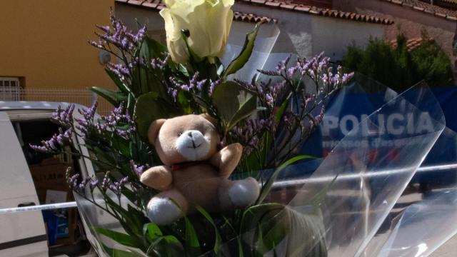 Una persona lleva un ramo de flores y un peluche al lugar en el que falleció un niño supuestamente a manos de su padre, en Girona.
