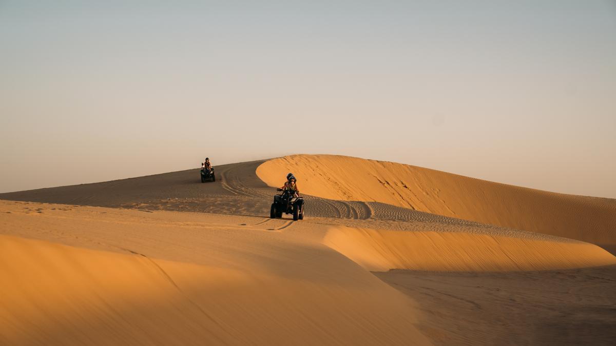Turistas recorriendo las dunas sobre un quad.