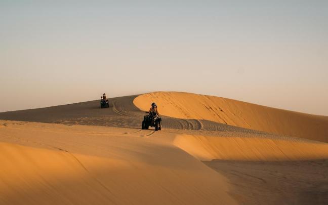 Turistas recorriendo las dunas sobre un quad.