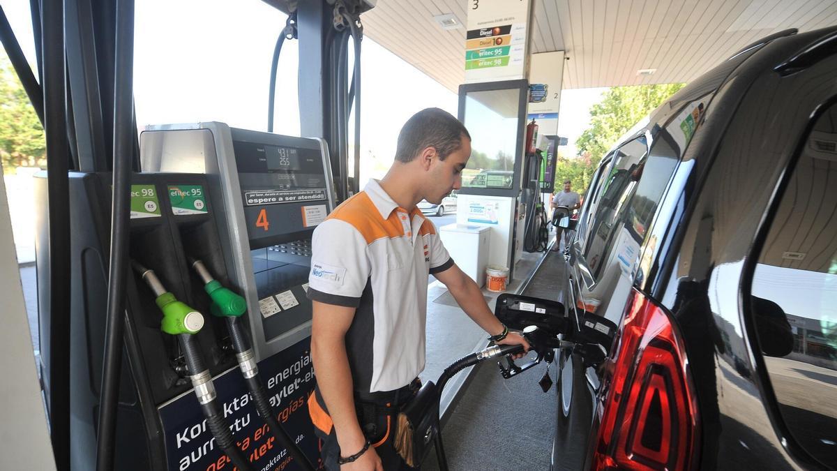 Un empleado de una gasolinera llena el depósito de un coche.