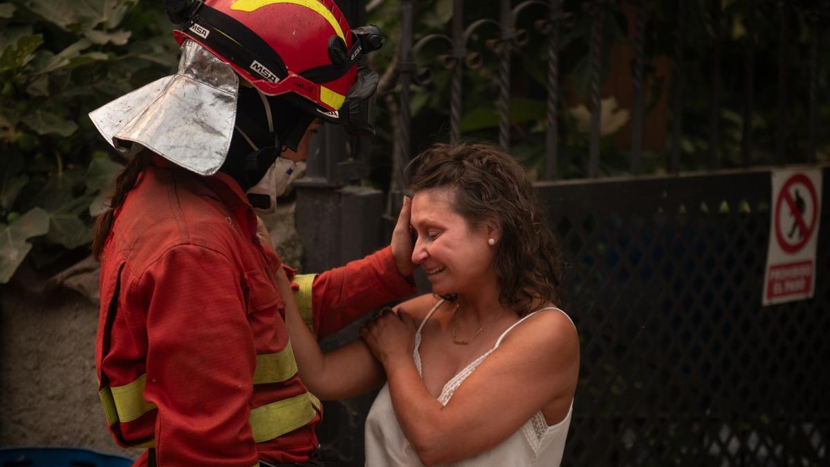 Una efectivo del UME consuela a una vecina de Piedralaves tras quemarse la casa de su padre durante el incendio de Burgohondo (Ávila).