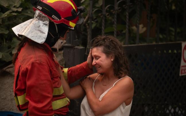 Una efectivo del UME consuela a una vecina de Piedralaves tras quemarse la casa de su padre durante el incendio de Burgohondo (Ávila).