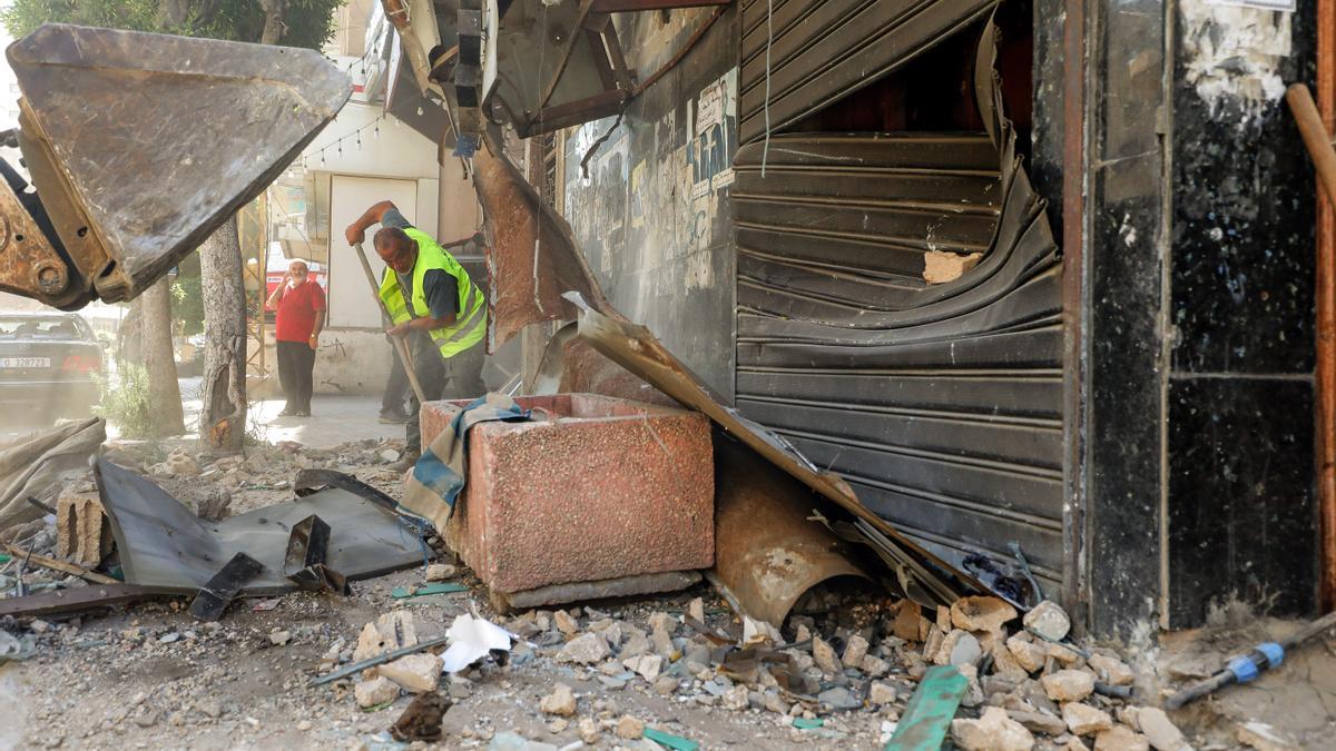 Un trabajador municipal retira escombros en el lugar de un edificio alcanzado por un ataque israelí.