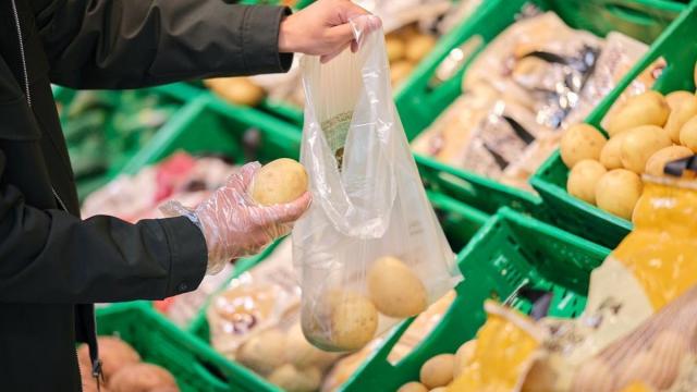 Una persona compra patatas en un supermercado.