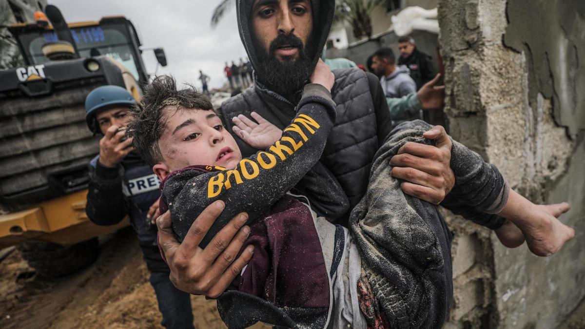 Una persona lleva a un niño herido y rescatado debajo de los escombros de su casa familiar, destruida tras un ataque aéreo israelí contra Deir Al Balah, en el sur de la Franja de Gaza.