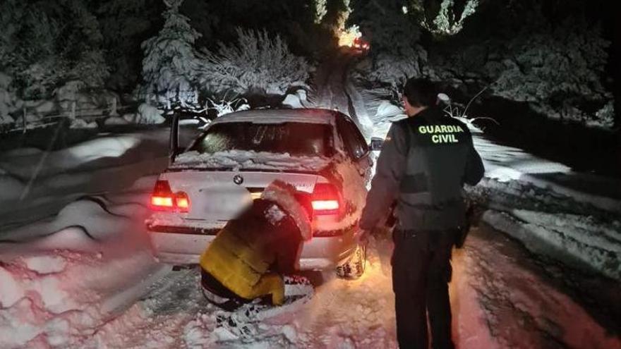 Un agente junto al turismo que quedó bloqueado por la nieve y su conductor.