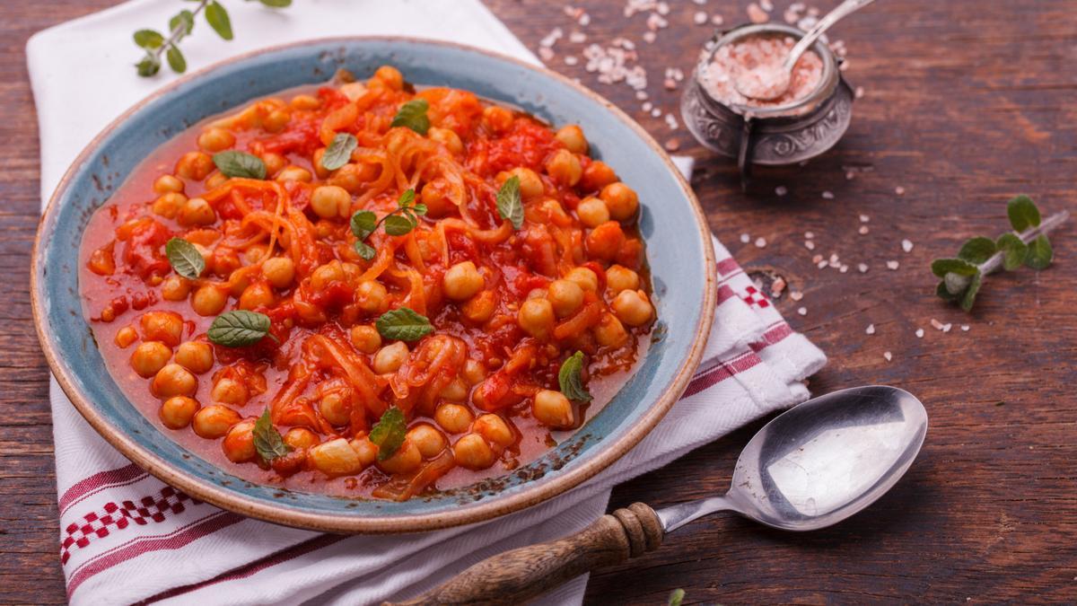 Un plato de garbanzos con pisto decorado con hierbabuena.