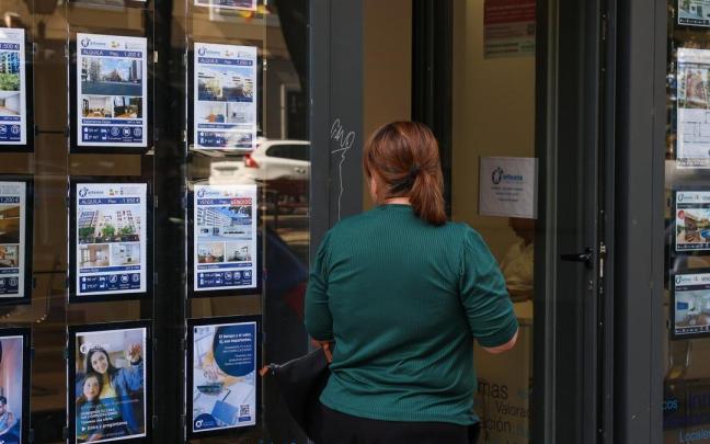 Una joven observa el escaparate de una inmobiliaria