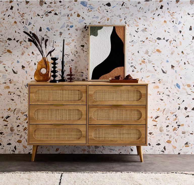 Una cajonera, varios elementos decorativos y una pared efecto terrazo crea un resultado de impacto visual.