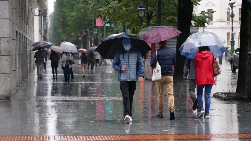 Ciudadanos pasean bajo la lluvia.