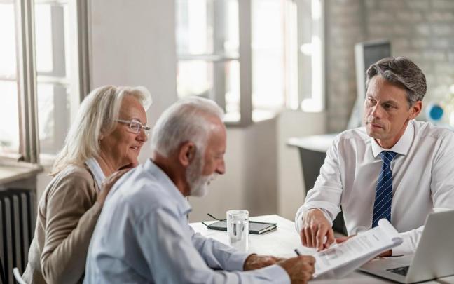 Una pareja mayor firma un contrato en un banco.