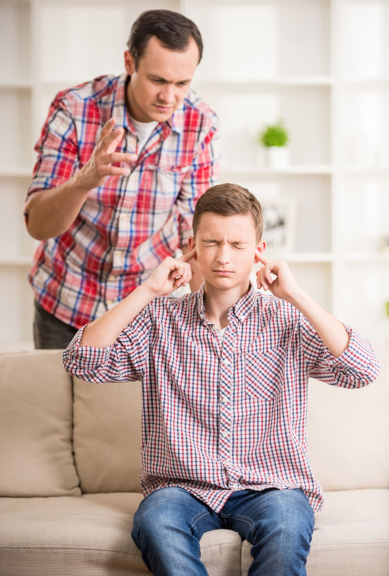 Un hijo adolescente se tapa los oídos para no escuchar a su padre.