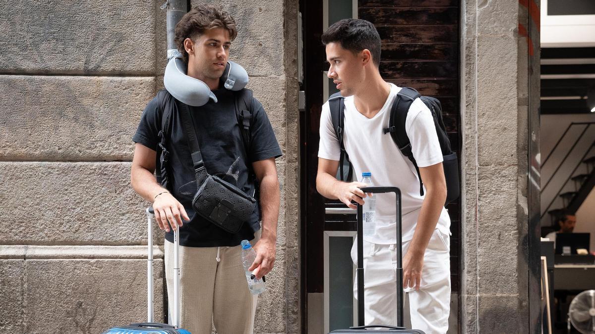 Dos jóvenes a las puertas de un edificio de apartamentos turísticos.