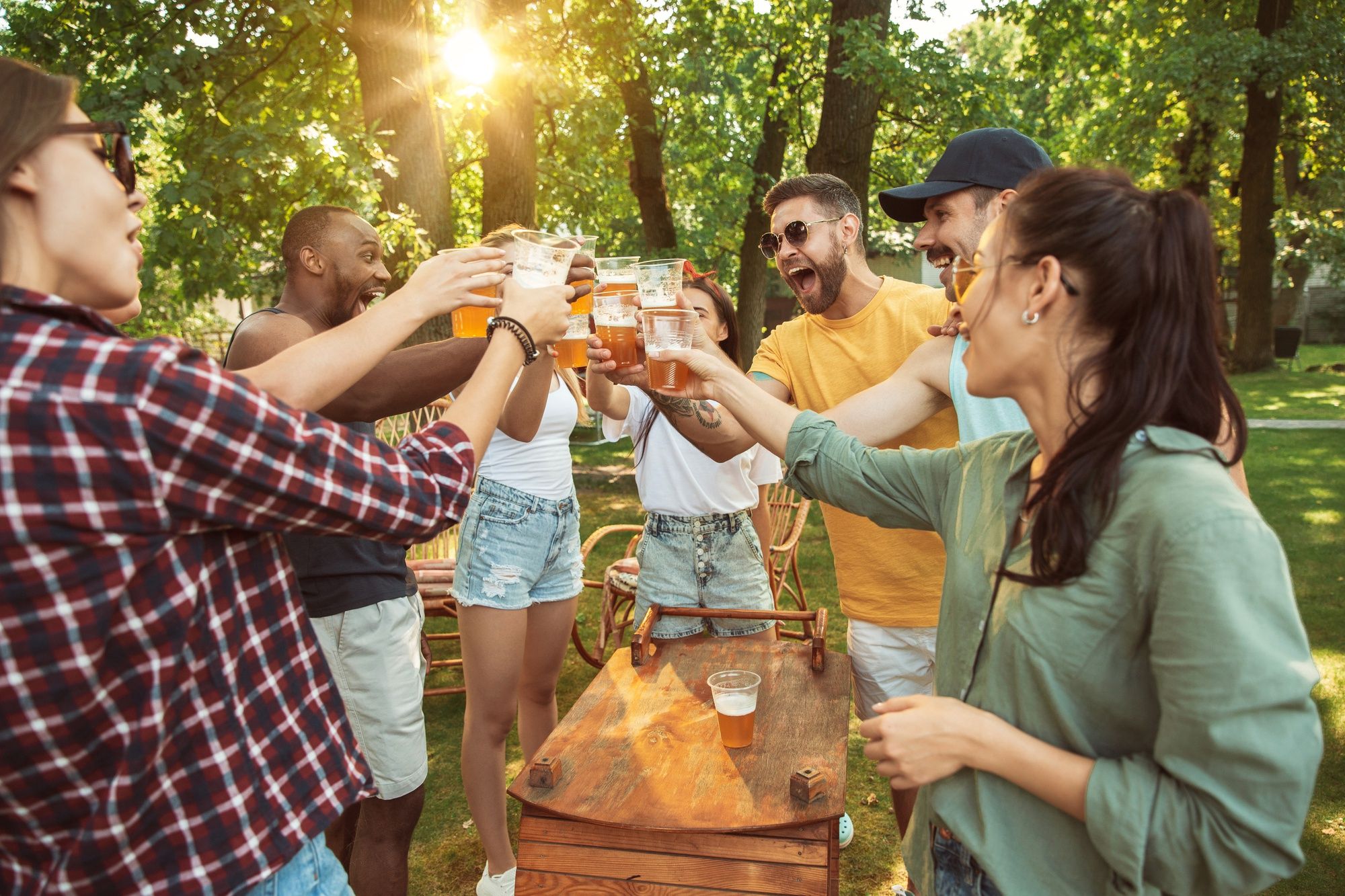 Un grupo de amigos brindan con cerveza en una barbacoa.