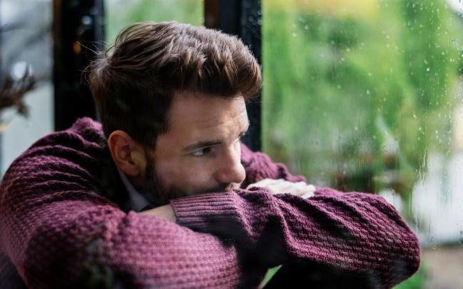 Un hombre desmotivado mira por una ventana en un día de lluvia. Un hombre desmotivado mira por una ventana en un día de lluvia.