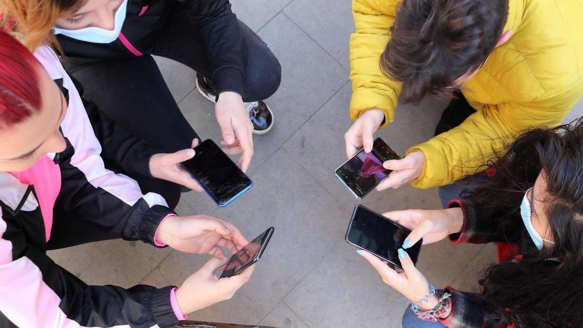 Un grupo de jóvenes miran sus teléfonos móviles