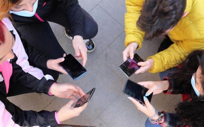 Un grupo de jóvenes miran sus teléfonos móviles Un grupo de jóvenes miran sus teléfonos móviles