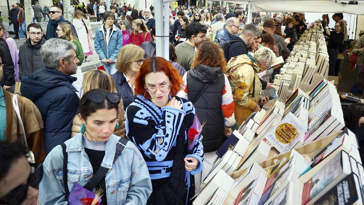Varias personas buscan libros en una parada del Paseo de Gracia de Barcelona durante la Diada de Sant Jordi.