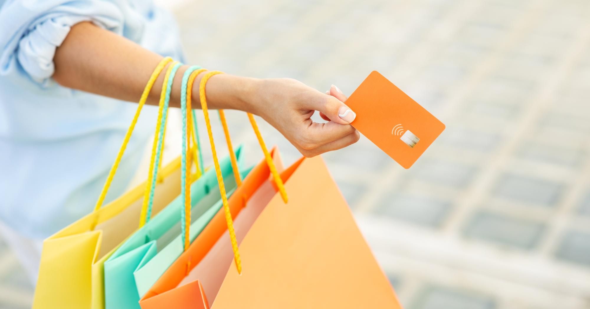 Una mujer sale de una tienda con bolsas y una tarjeta regalo.