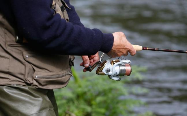 Detalle de la caña de pescar de un hombre durante el comienzo de la campaña de pesca de salmón