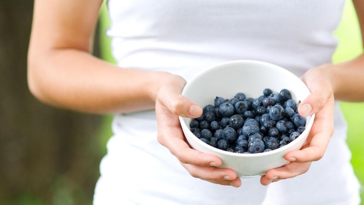 Chica sujeta un bol de arándanos